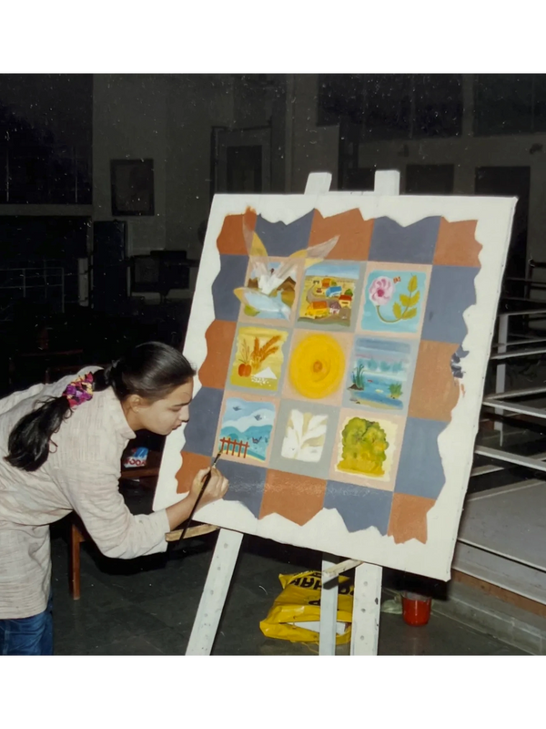 A woman painting colorful squares on a canvas in an indoor setting.