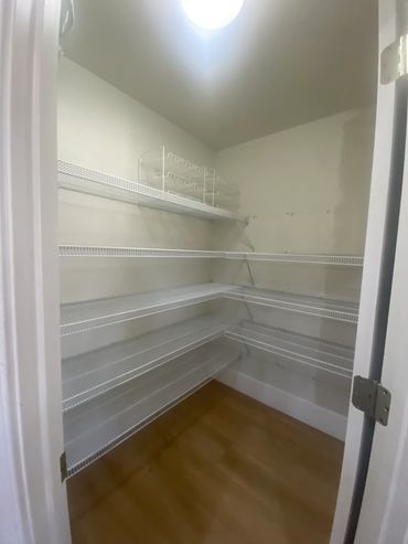 Empty pantry with white wire shelves and wooden floor.