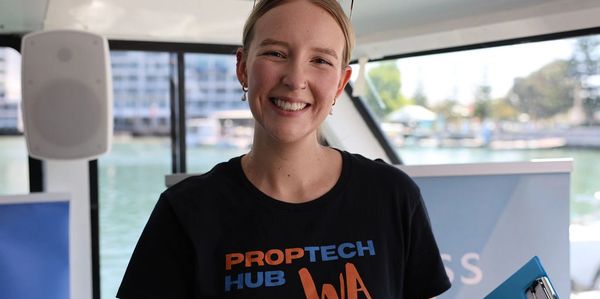 Smiling woman in a PropTech Hub WA shirt on a boat.