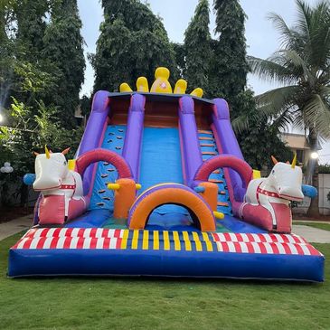 Colorful inflatable unicorn-themed slide set up on a lawn.
