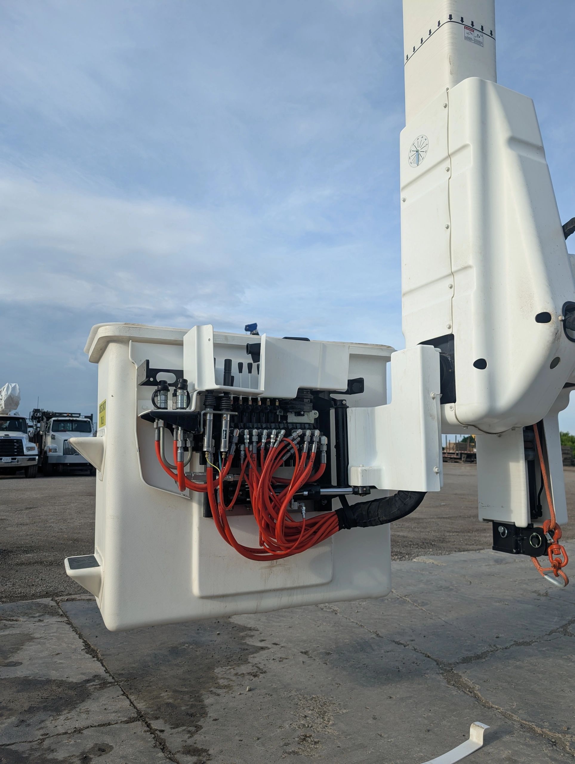 Close-up of hydraulic controls and red hoses on a white industrial machine.