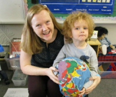 teacher and little boy holding a pillow globe