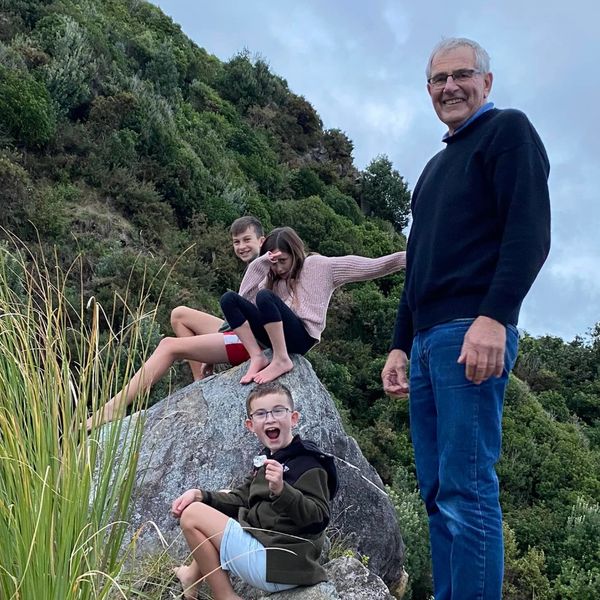 Grandfather and three children climbing rocks with happy faces