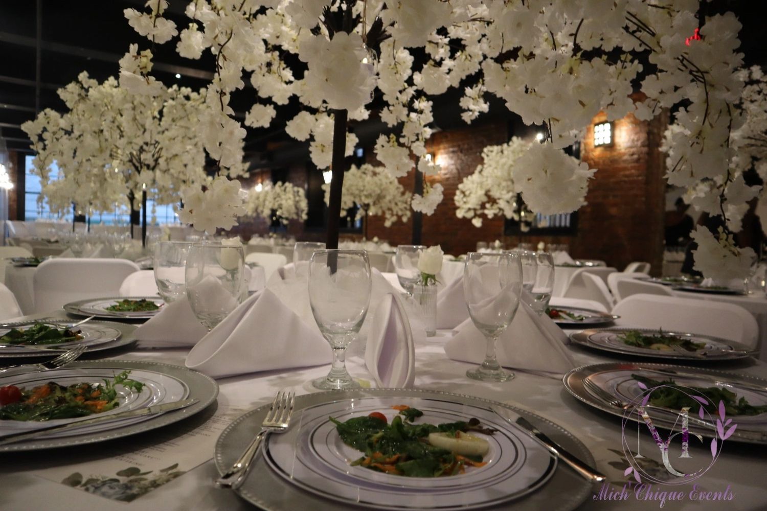 At the center of each table stands a tall, silk-feel white blossoms, adding height and elegance.