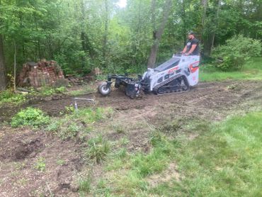 Machine raking a rough area in yard
