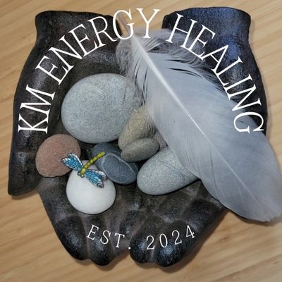 A palm-shaped dish holds healing stones and a white feather, labeled KM Energy Healing EST. 2024.