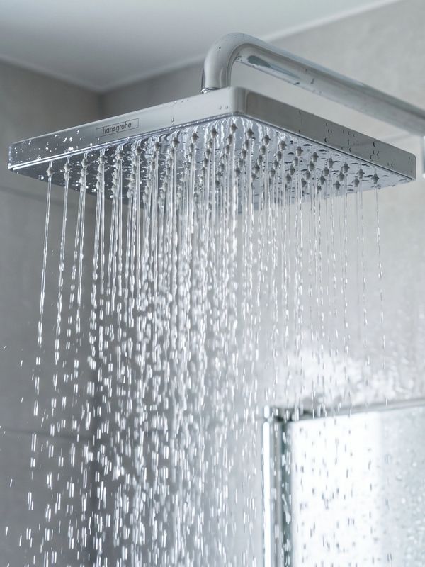Modern square rain showerhead releasing water streams.
agua limpia para bañarse
