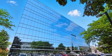 Modern glass office building reflecting the blue sky and clouds.