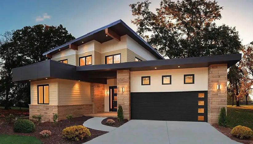 Modern two-story house with stone and wood exterior at dusk.
