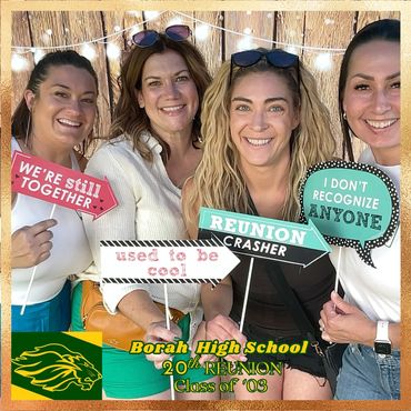 Four women smiling at Borah High School's 20th reunion with playful signs.
