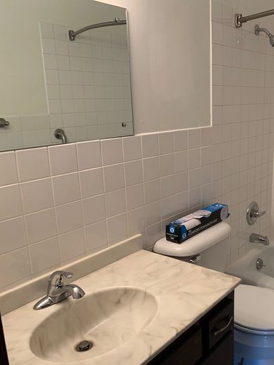 Bathroom sink with marble countertop and toilet in the background.