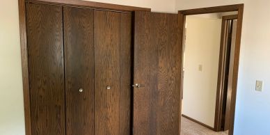 Empty room with wooden closet doors and an open door.