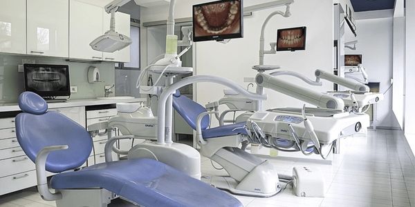 Modern dental clinic with blue dental chairs and digital screens.