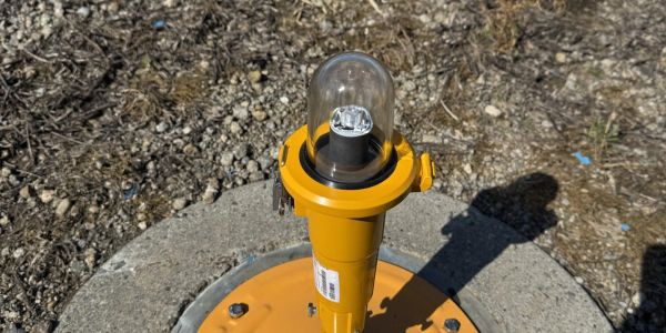 Yellow light bulb installation on a concrete surface outdoors.