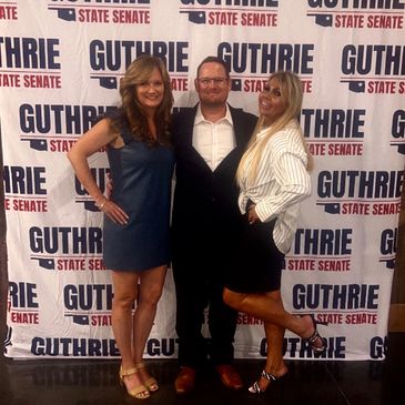 Three people posing in front of a campaign backdrop for Guthrie State Senate.