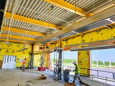 Construction workers installing fixtures inside a building under construction.