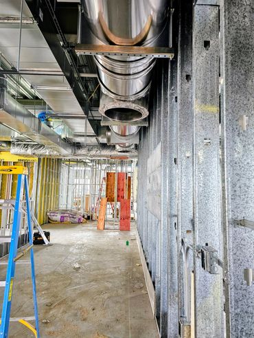 Interior view of a construction site with exposed ducts and metal framing.