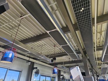 Industrial ceiling with hanging lights and ventilation ducts.