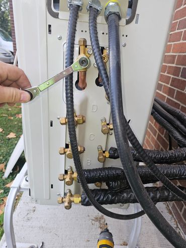 Hand tightening a bolt on an air conditioning unit with a ratchet wrench.