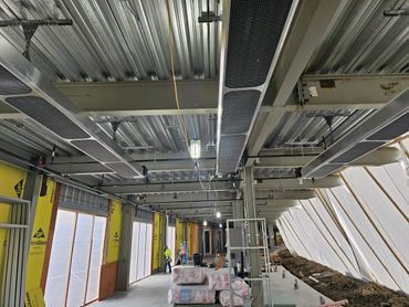 Interior view of a commercial building under construction with exposed ceiling and insulation.