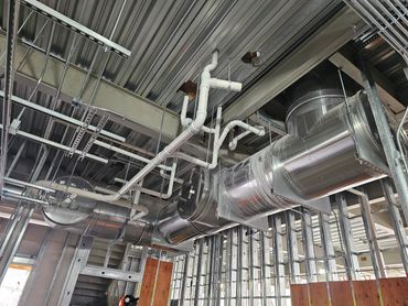 Exposed HVAC ductwork and piping in a building under construction.