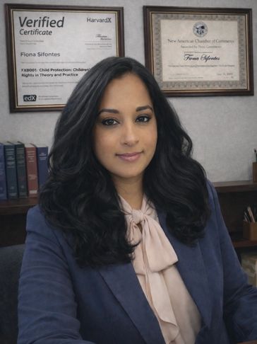 Professional woman sitting in office with certificates behind her.
