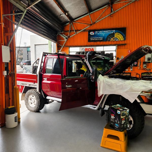Red pickup truck being repaired in a garage.