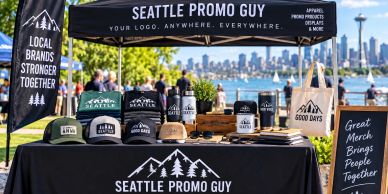 Seattle Promo Guy merch stand by the water with city skyline.
