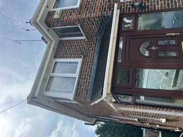 Exterior view of a brick house with white-framed windows and a brown front door.