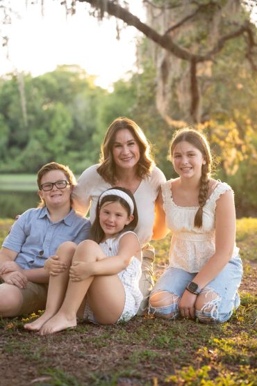 Smiling family sitting outdoors during golden hour.