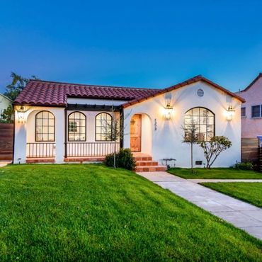 Charming Spanish-style house with red tile roof and warm exterior lighting at dusk.