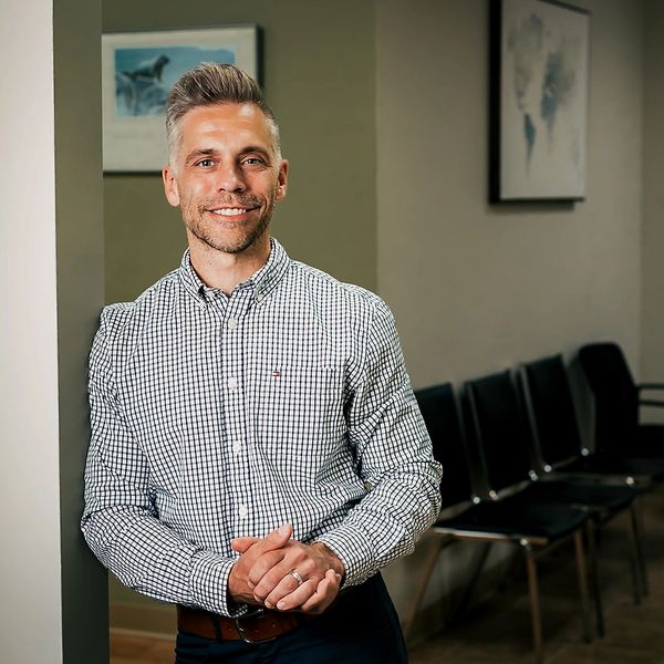 Man in checkered shirt smiling indoors.