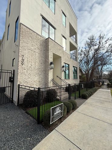 Black ornamental metal fence beside a modern Houston Heights townhome