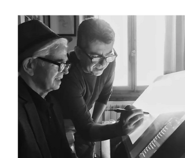 Two men collaborating on a digital drawing tablet in a bright room.