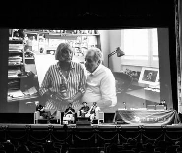 Panel discussion in theater with large black and white photo projected behind.