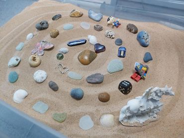 A sandtray creative exercise showing different stones and objects laid in a swirl pattern