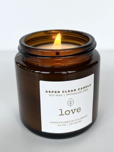Lit soy wax candle in amber glass jar labeled 'love'.