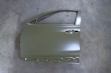 A silver car door without a window or handle on a concrete floor.