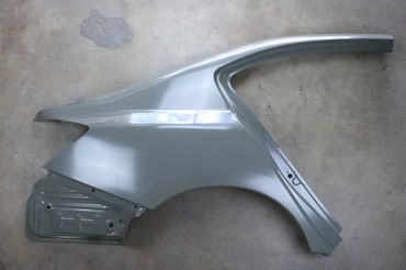 A silver car quarter panel on a concrete floor.