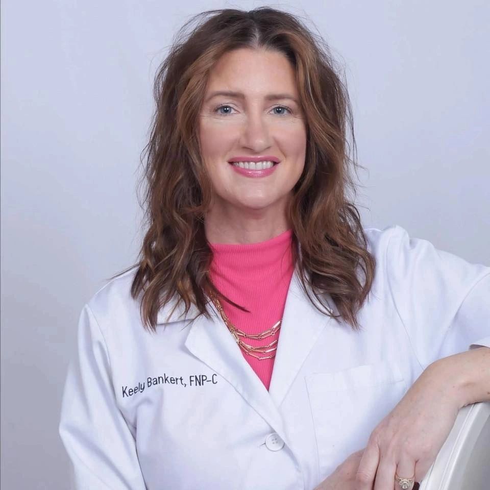 Smiling female healthcare professional in white coat with pink top.