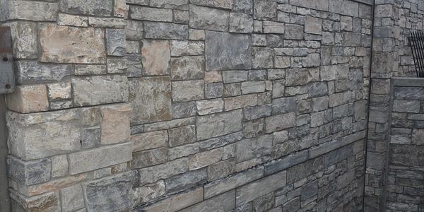 Stone wall with varied rectangular blocks and a concrete floor at dusk.