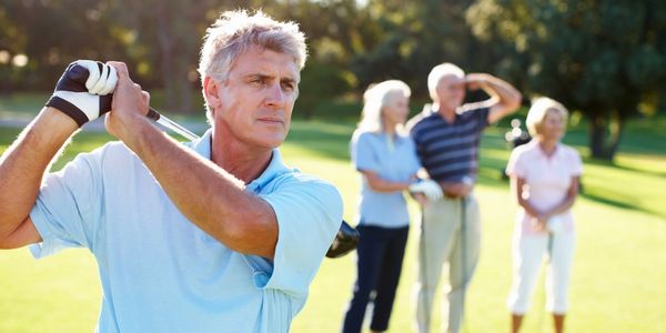 A man golfing with his wife and another couple watching.