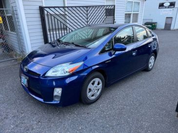 Blue Toyota Prius parked on a driveway beside a house.