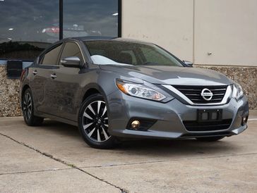 A gray Nissan sedan parked outside a building.
