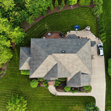 Aerial view of a suburban house with a manicured lawn and driveway.