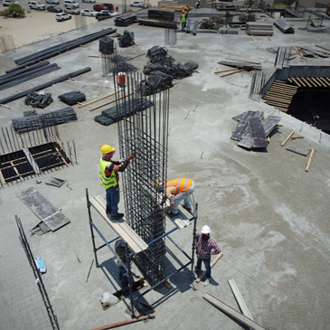 Construction workers reinforcing concrete with steel rebar on site.