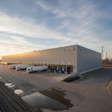 Large warehouse with multiple loading docks and trucks parked outside.