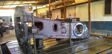 Large metal industrial part secured on a machine table in a workshop.