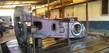 Large metal industrial part secured on a machine table in a workshop.