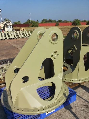 Large beige industrial metal components with circular cutouts on blue pallets.